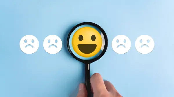 row of emoji faces, 4 grumpy and one in the middle smiling