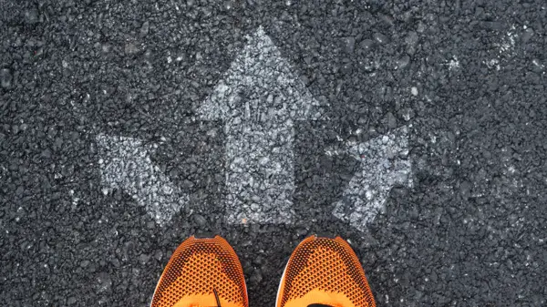 Arrows in different directions painted on ground, orange trainers facing the arrows