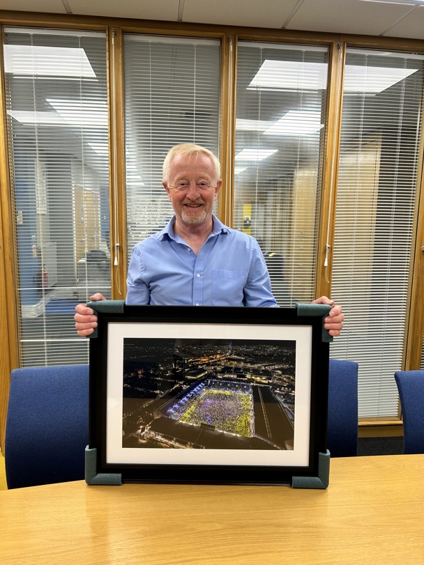 Chris holding a framed photo of Fratton Park football ground
